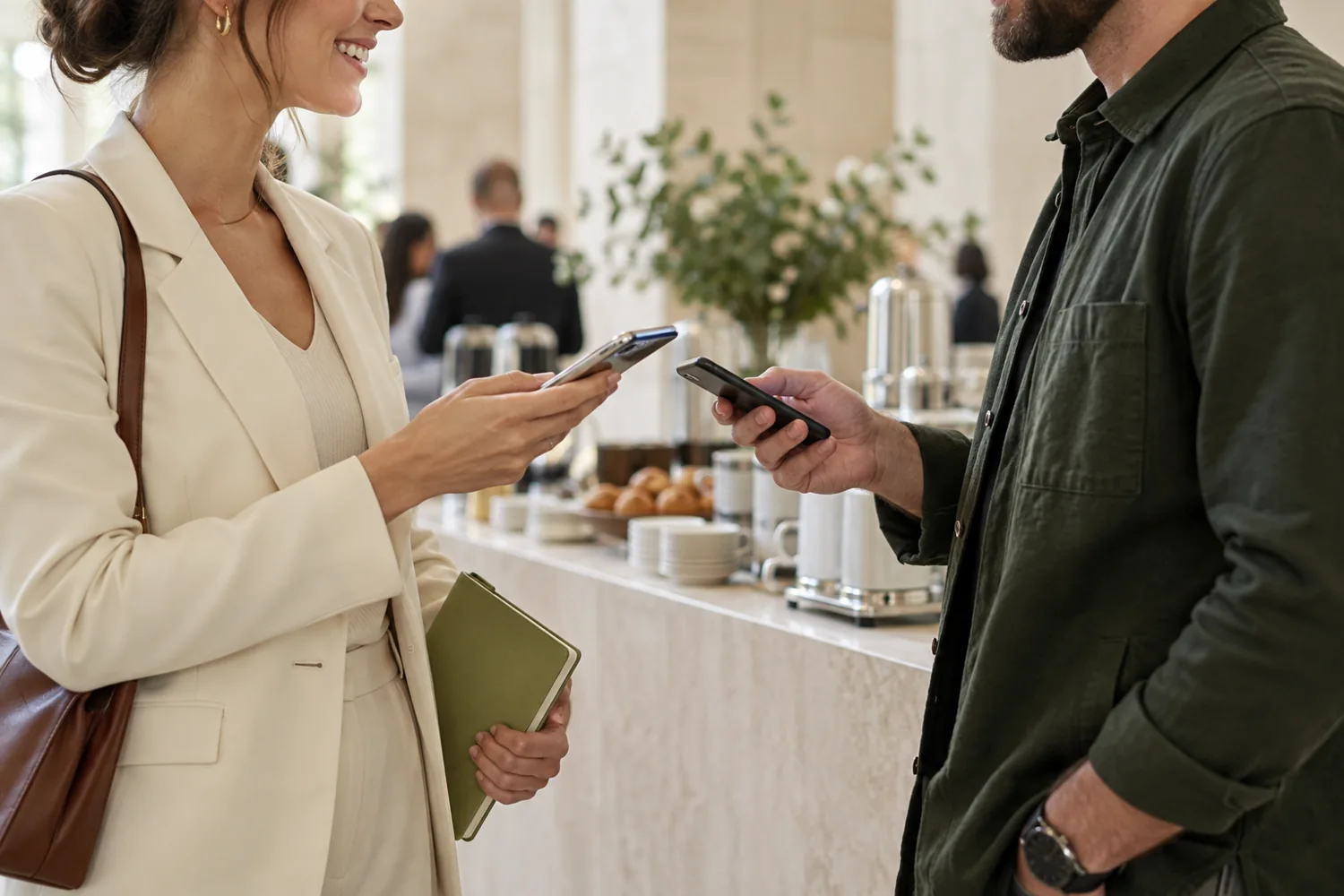 Two professionals exchanging contact details with their phones at a conference coffee bar